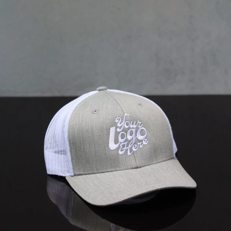 Front view of a custom embroidered grey and white trucker hat with mesh back and logo placeholder